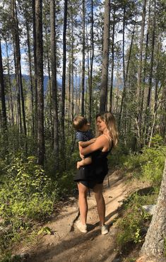 a woman holding a child in the woods