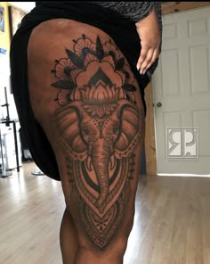 an elephant tattoo on the back of a woman's thigh, with flowers around it