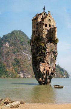 an island with a castle built on it in the middle of water next to a mountain