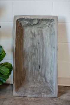 a concrete block sitting on top of a floor next to a potted green plant