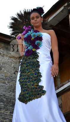 a woman in a white dress with peacock feathers