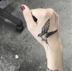 a person with a bird tattoo on their left arm and hand holding something in the air