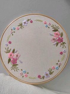 a white cloth with pink and blue flowers on it in front of a wooden hoop