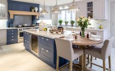 a large kitchen with blue cabinets and white counter tops, an island in the middle