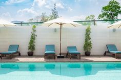 an empty swimming pool with lounge chairs and umbrellas next to the side of it