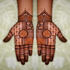 two hands with henna designs on them, one is brown and the other is orange