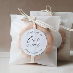 two bagels wrapped in white paper and tied with twine on the top one has a tag that says,'give us sweet '