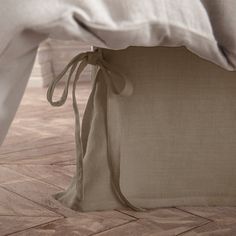 the back of a bed with white linens and pillows on it, tied up