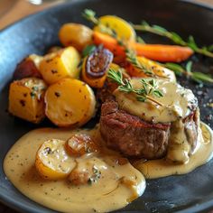 a steak with gravy and potatoes on a black plate next to carrots