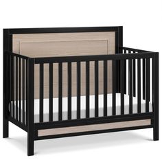 a black crib with white sheets on the bottom and beige bedding underneath it