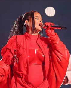 a woman in a red outfit singing into a microphone