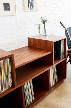 an old record player is sitting on a shelf next to a wall with records in it