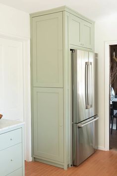 a large stainless steel refrigerator in a kitchen with white walls and wood flooring on the side