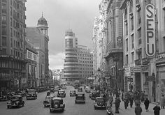 an old black and white photo of cars on a city street with tall buildings in the background