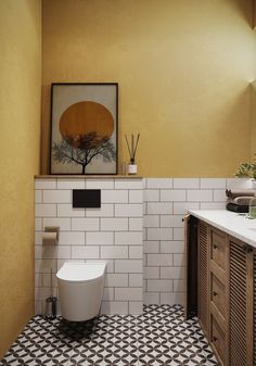 a white toilet sitting next to a sink in a bathroom under a painting on the wall