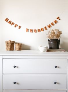 a white dresser topped with a potted plant next to a sign that says happy engagement