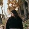 a woman and child are walking down the street in front of an old cemetery with tombstones