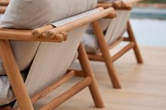 two wooden chairs sitting next to each other on top of a hard wood floor near a pool