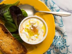 a yellow plate topped with bread and salad next to a bowl of yogurt