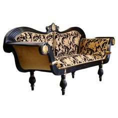 an ornate black and gold couch with wooden legs