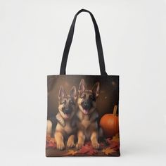 two german shepherd puppies sitting on leaves in front of a pumpkin tote bag