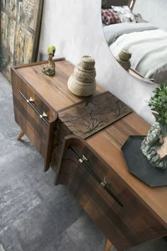 a wooden table with a mirror on top of it next to a plant and vase