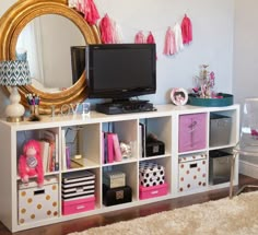 a tv sitting on top of a white shelf next to a mirror and other items