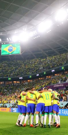 a group of soccer players huddle together on the field in front of an audience