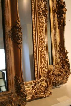 an ornate gold framed mirror sitting on top of a table