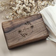 a wooden box sitting on top of a table next to some flowers and napkins