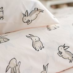 the bedding has rabbits on it and is white with black outlines, as well as two pillow cases