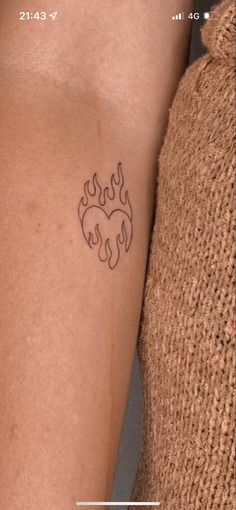 a woman's arm with a tattoo on it that has flames coming out of it