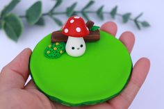 a hand holding a small green cake with a mushroom on it