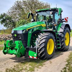 a green tractor parked on top of a dirt road