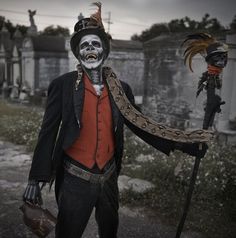 a man dressed up as a skeleton with feathers on his head and an orange shirt