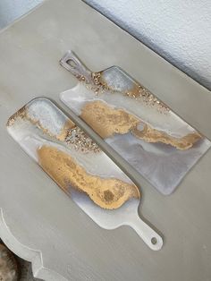 two white and gold serving trays sitting on top of a table