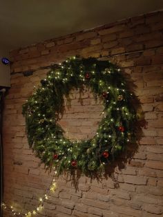 a christmas wreath is hanging on the wall above a bed in a room with brick walls