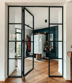 an open glass door leading into a room with wood floors and white walls in the background