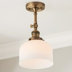 a light fixture with a white glass shade hanging from it's center point on the ceiling