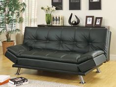 a black leather futon sofa sitting on top of a hard wood floor