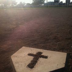 a concrete cross sitting in the middle of a baseball field with dirt all over it