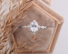 an engagement ring with three stones on top and two diamonds in the middle, surrounded by dried grass