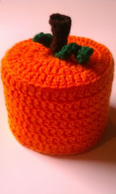 an orange crocheted container with a small black object on top