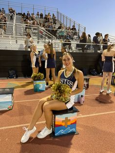 a cheerleader sitting on a bench in front of a crowd