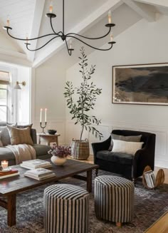 a living room filled with furniture and a chandelier hanging from the vaulted ceiling