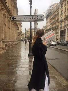 a woman is standing on the street reading a newspaper