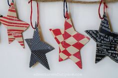 four wooden stars hanging from a rope on a wall with words written in them and red, white, and blue designs