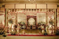 a decorated stage set up for a wedding ceremony with pink flowers and greenery on the floor