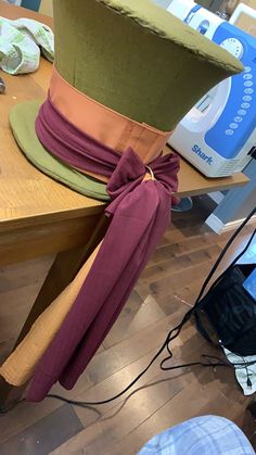 a green hat with a bow tied around it on top of a wooden table next to other items