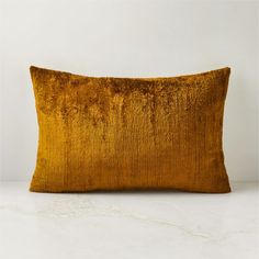 an orange velvet pillow on a white surface